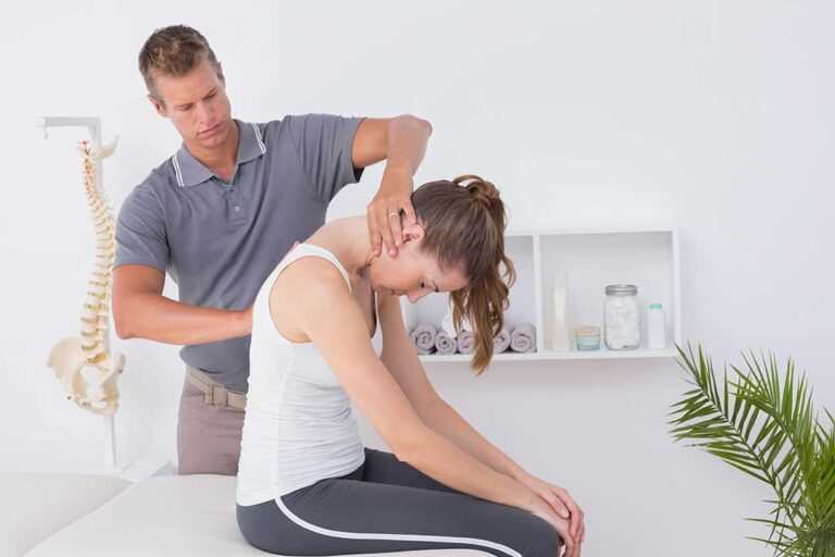 A chiropractor gently adjusting a woman’s lower back in a calm clinical setting.