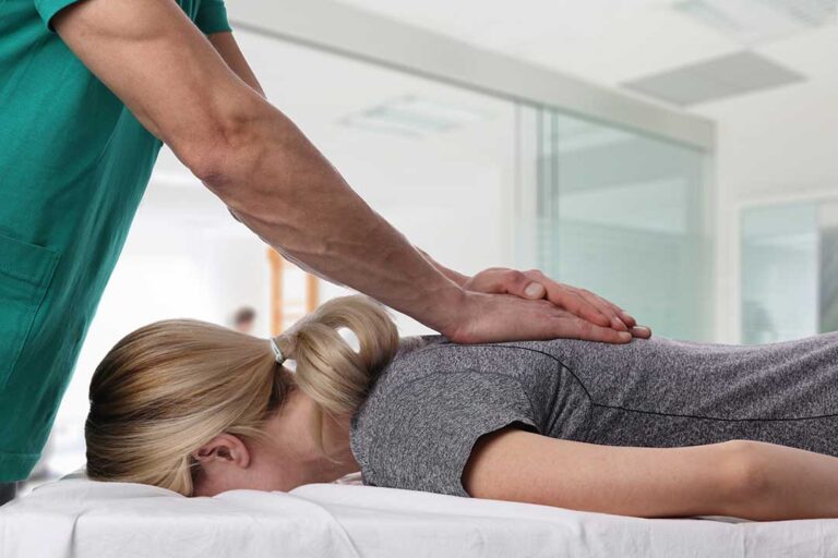 Person gently stretching a tight upper back beside a desk, with shoulder muscles visibly tense.
